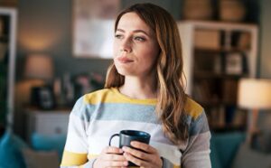 Image of a woman in a living room holding a mug.